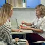 Gynecologist holding female uterus anatomy model and explains Tubal Ligation to patient