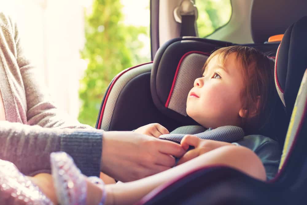 Toddler girl in her car seat looking at her mothers