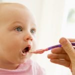 Mother feeding baby food to baby and it makes a face