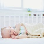 Baby rolling on side in bassinet