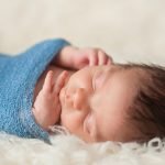 Baby with hands out of its swaddle
