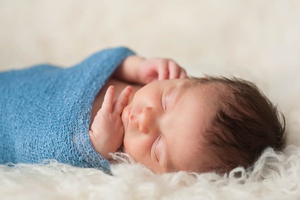 Baby with hands out of its swaddle