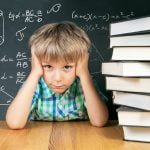 Young boy thinking about math problem in front of chalkboard