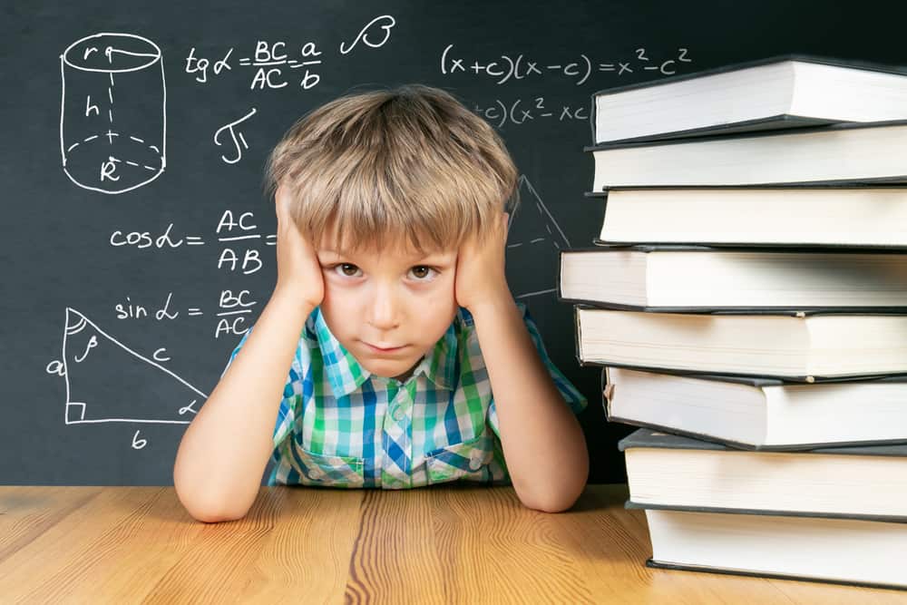 Young boy thinking about math problem in front of chalkboard