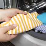 Woman put stained baby cloths in washingmachine