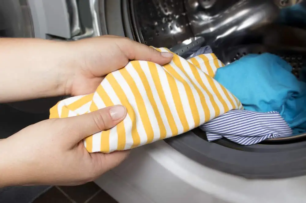 Woman put stained baby cloths in washingmachine
