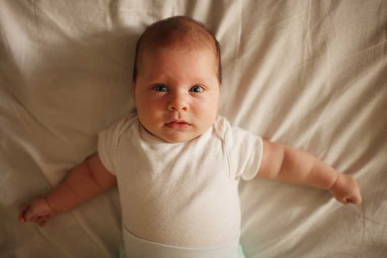 Newborn with bloated belly looking at camera