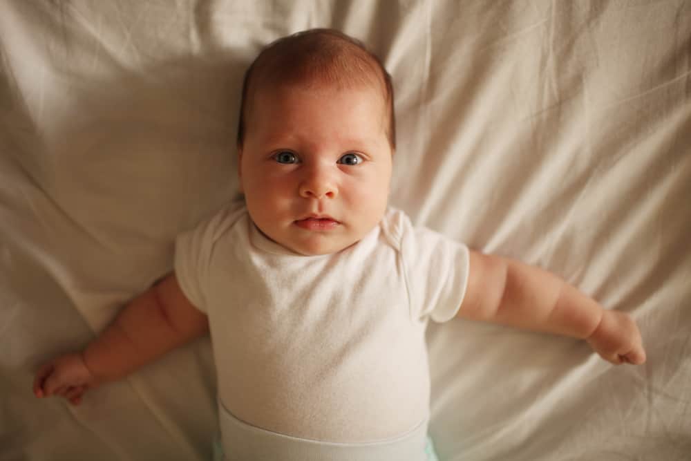 Newborn with bloated belly looking at camera