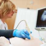 Ultrasound test. Pregnancy. Gynecologist checking fetal life with scanner.
