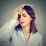 pregnant woman wipes sweat from her forehead with a handkerchief because of hot flashes