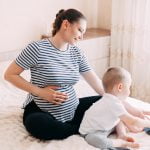 woman that is pregnant again playing and hugging with her second baby