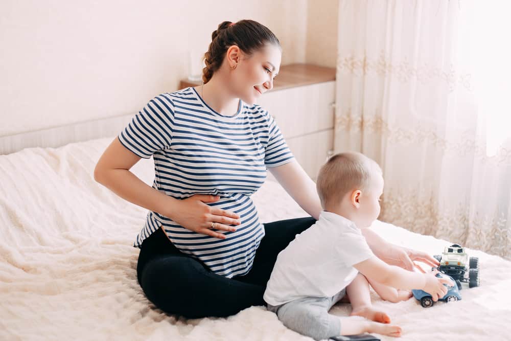 woman that is pregnant again playing and hugging with her second baby